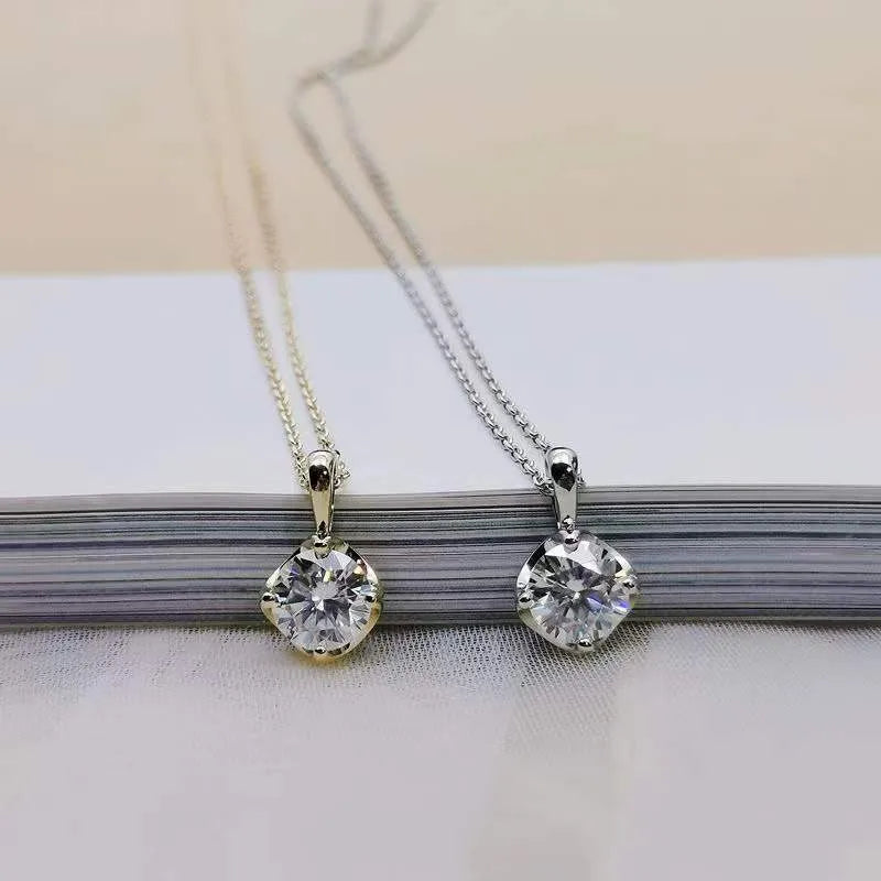 Two silver pendants with clear stones on a white surface