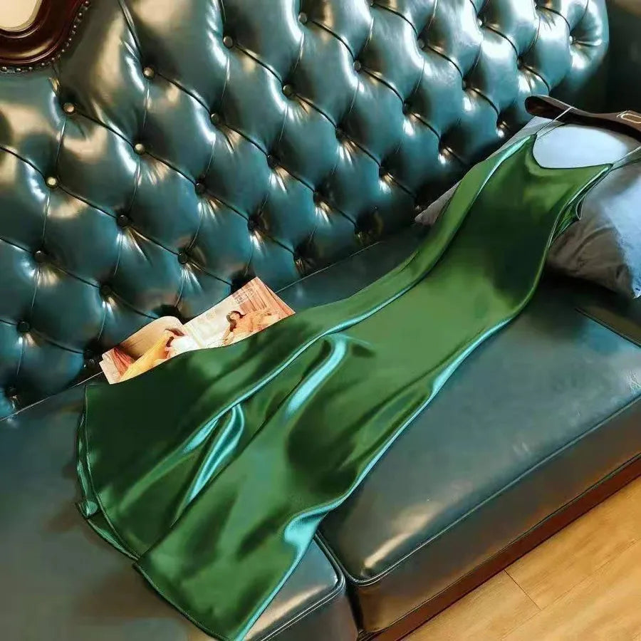 Green satin fabric draped over a teal tufted sofa with a magazine underneath.