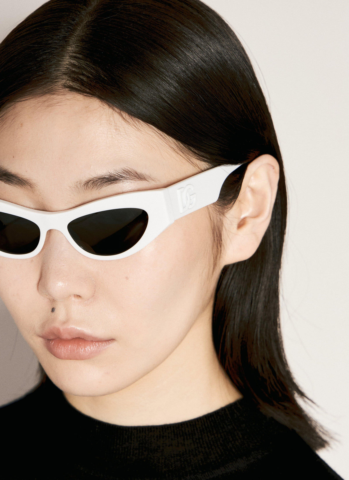Person wearing white sunglasses with black lenses against a neutral background