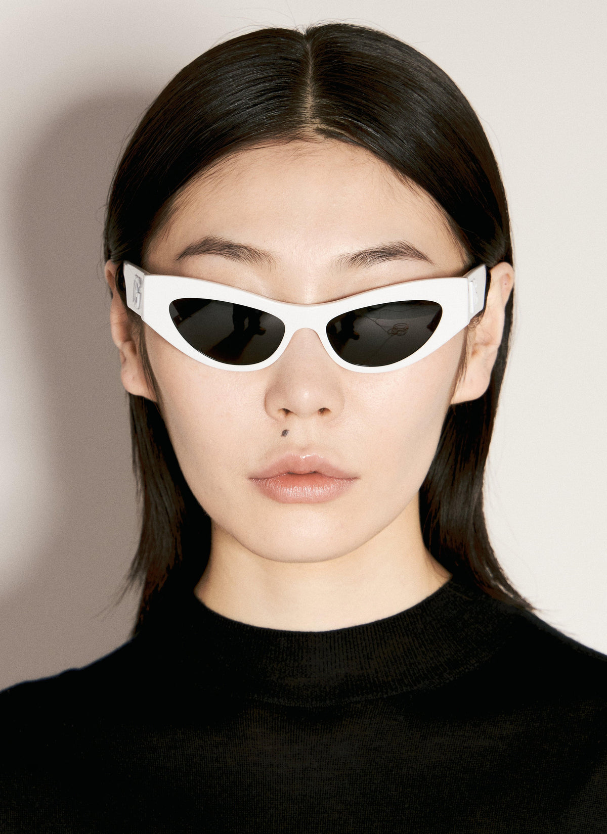 Person wearing white sunglasses with a neutral background