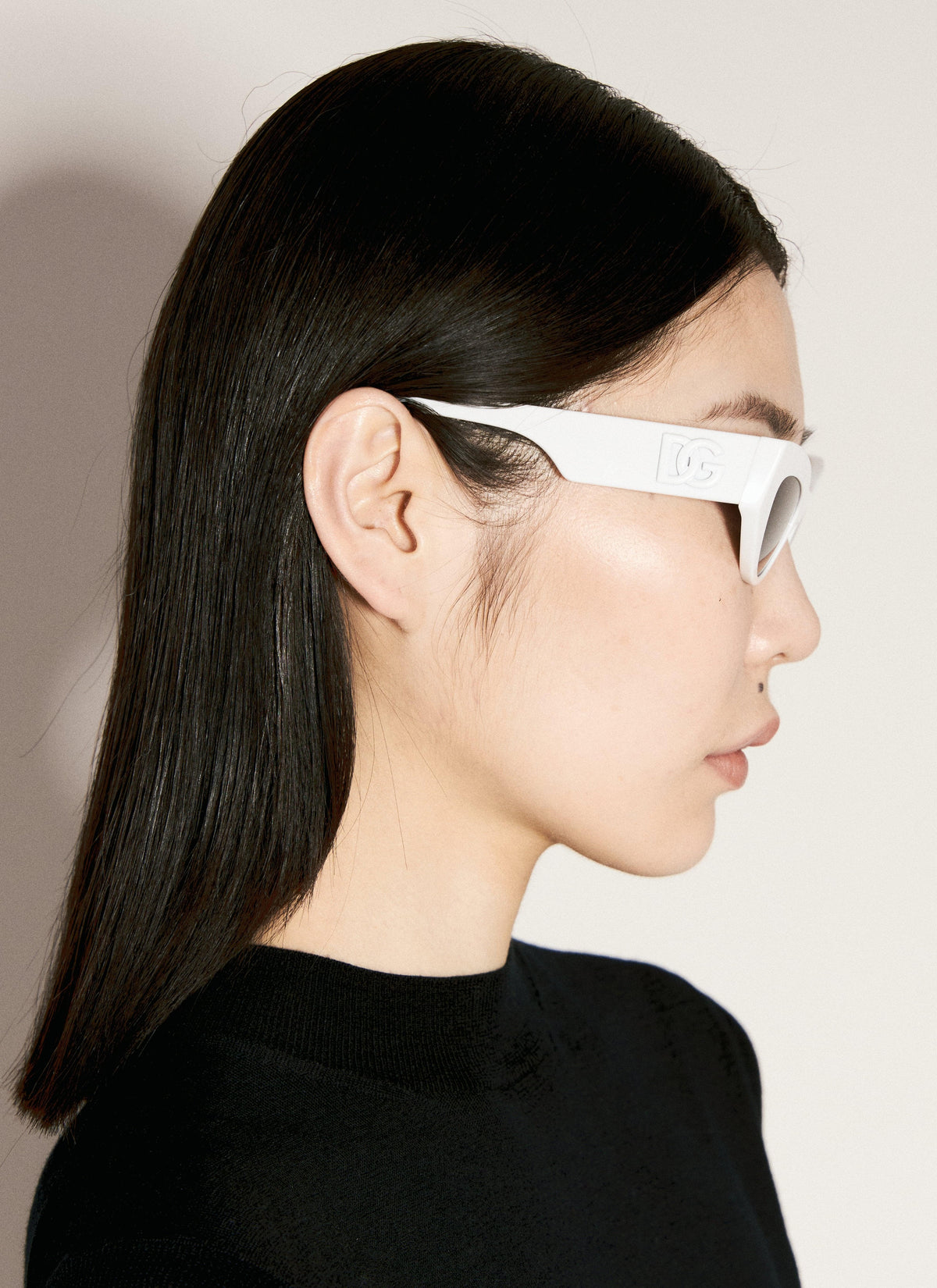 Person wearing white sunglasses with a neutral background