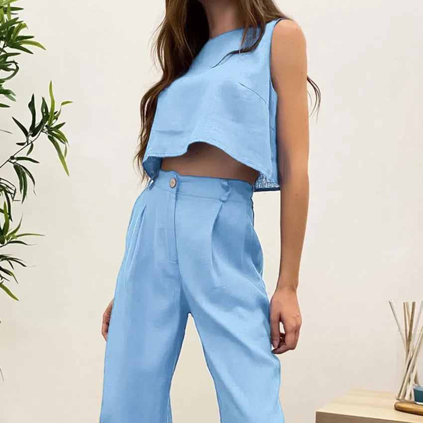 Person wearing a light blue sleeveless top and pants against a neutral background