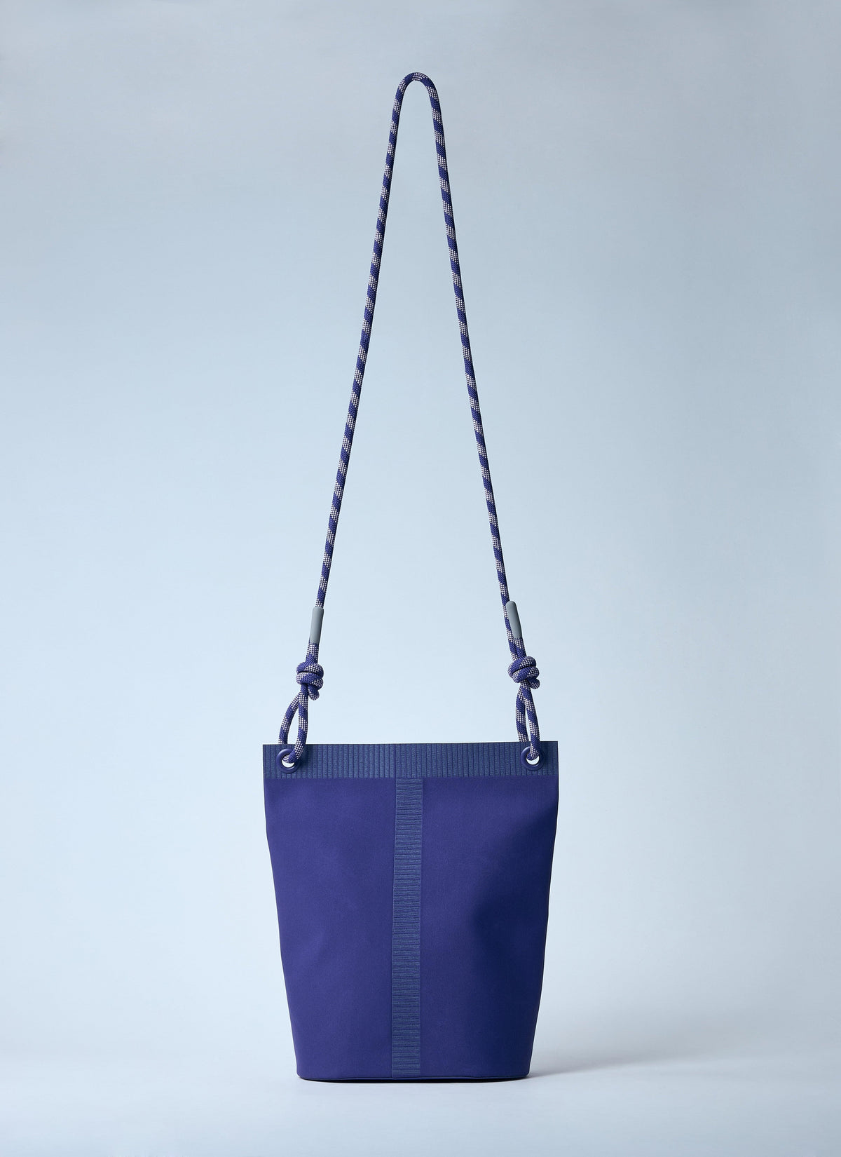 Blue bucket bag with a rope handle on a light gray background