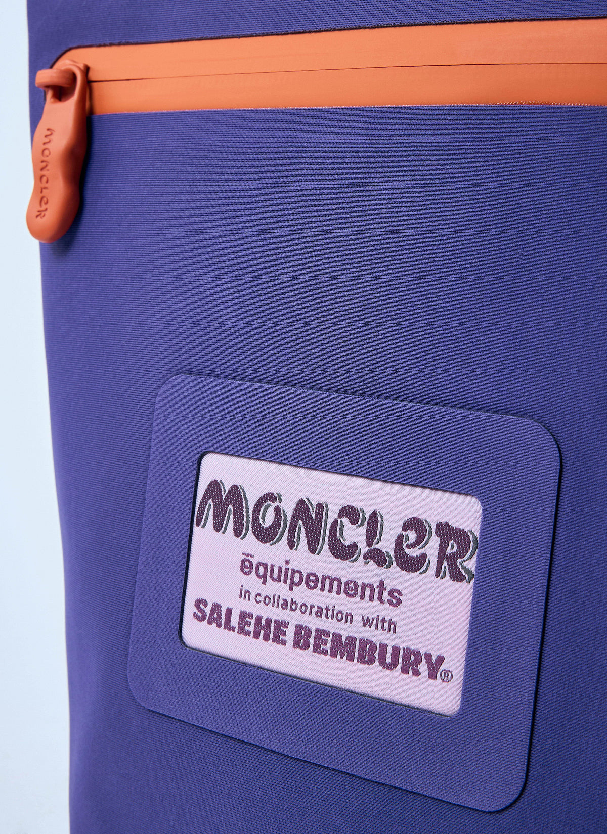 Blue bag with a Moncler and Salehe Bembury label on a light purple background