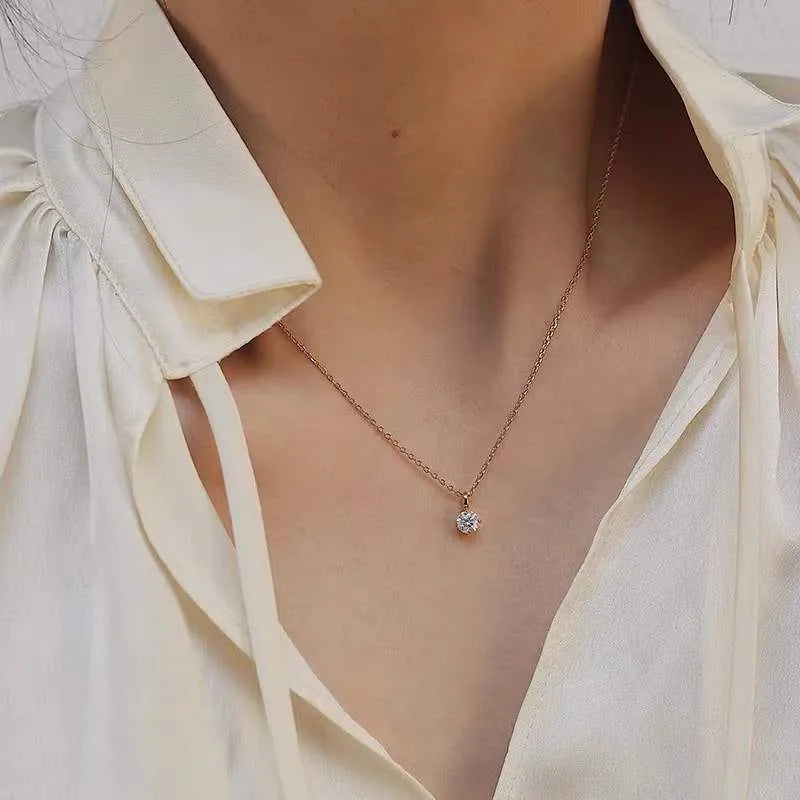 Necklace with a small pendant worn by a person in a light-colored shirt.