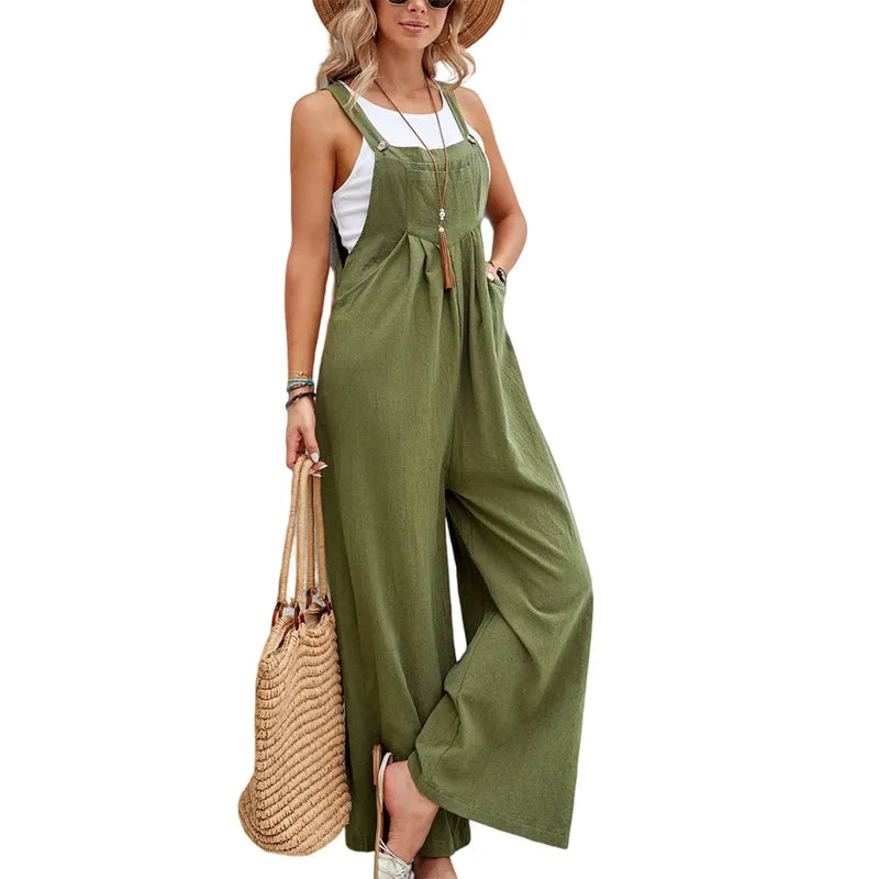 Woman wearing a green jumpsuit with a white top, holding a straw bag on a white background