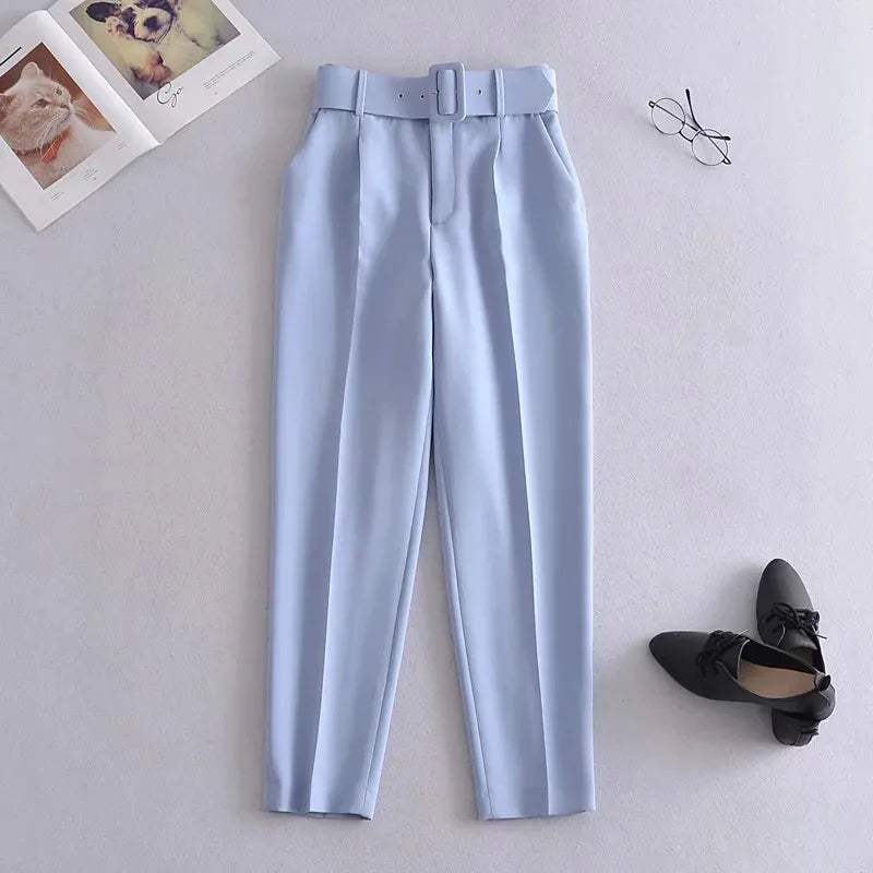 Light blue pants with a belt on a light gray background, accompanied by black shoes and glasses.