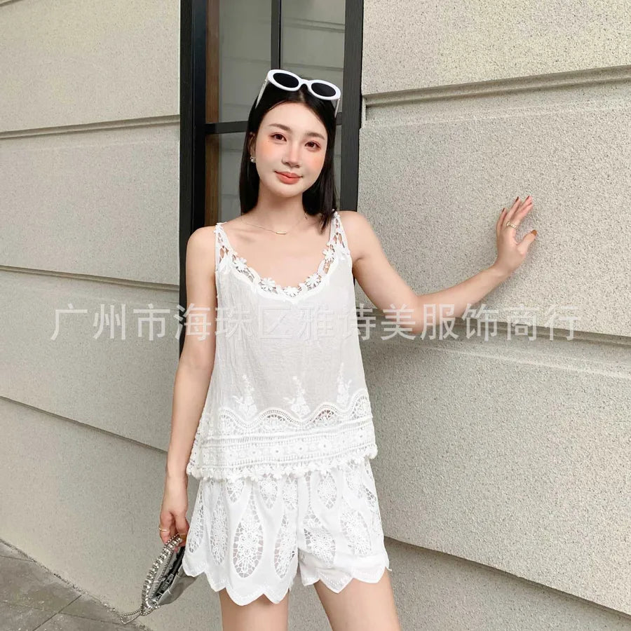 Woman wearing a white lace outfit standing against a light-colored wall.