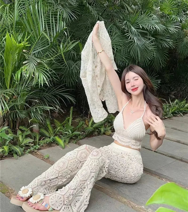 Woman in a white lace outfit sitting on a stone path with greenery in the background