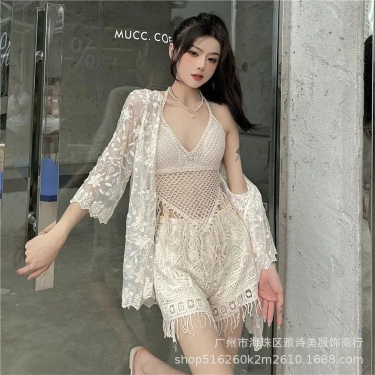 Woman wearing a white lace outfit standing in front of a glass door.