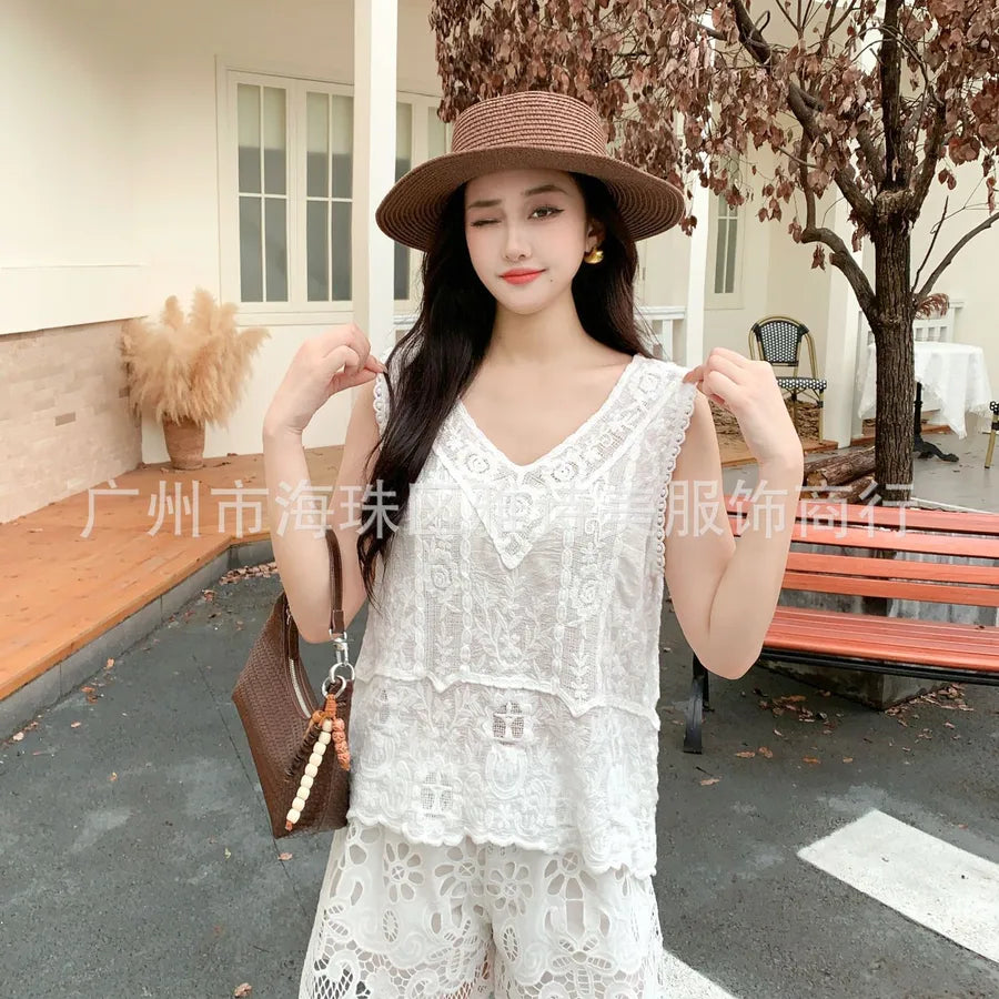 Woman in a white lace outfit and brown hat standing outdoors.