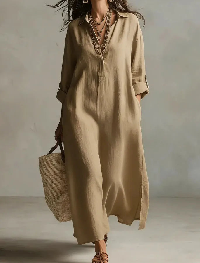 Woman wearing a beige long dress holding a woven bag against a neutral background