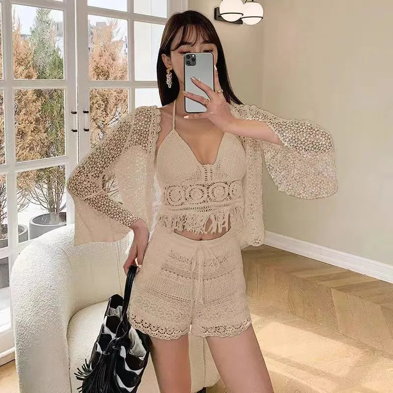 Woman taking a mirror selfie wearing a beige lace outfit in a room with a window and chair.