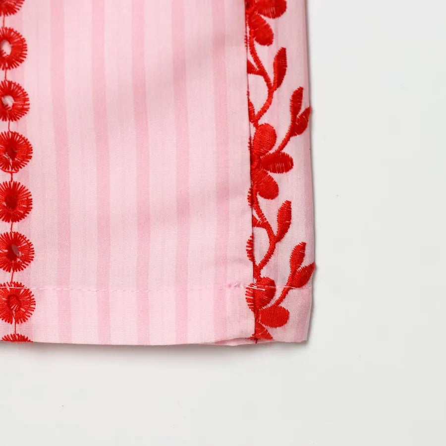 Pink fabric with red floral embroidery on a white background pink pants with red flowers