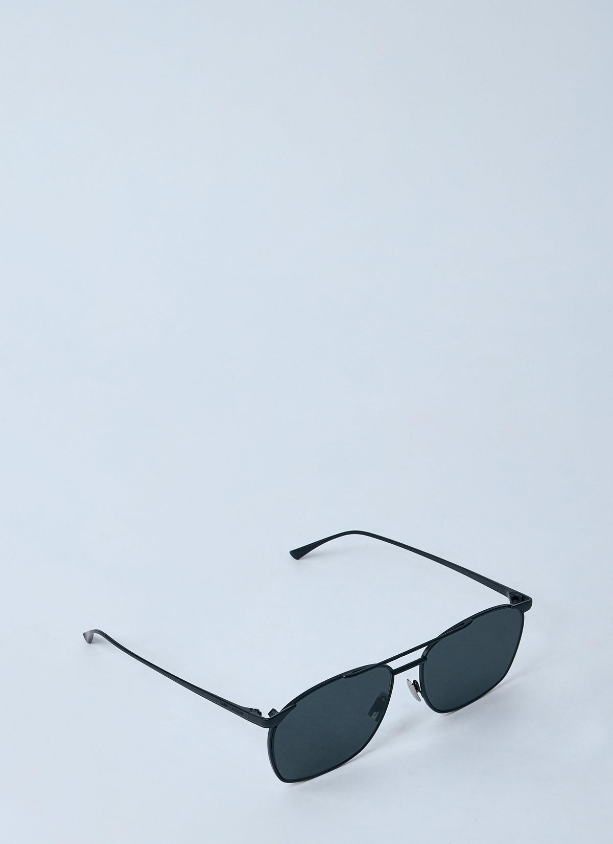 Gold-framed sunglasses with black lenses on a light gray background